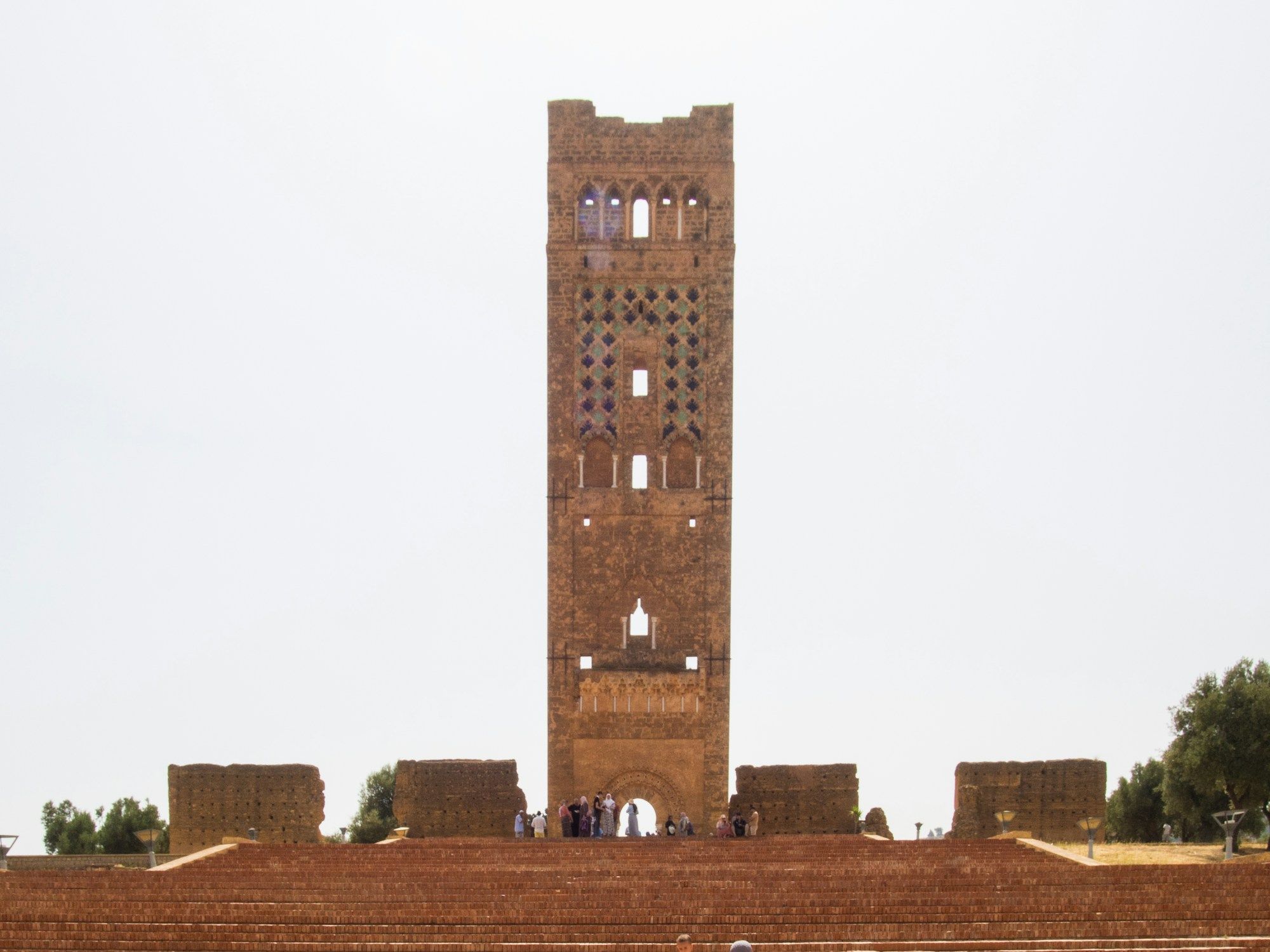 Le minaret de Mansourah, haute tour carrée de pierre ocre percée d’arcatures, entre deux pans de murailles en ruine